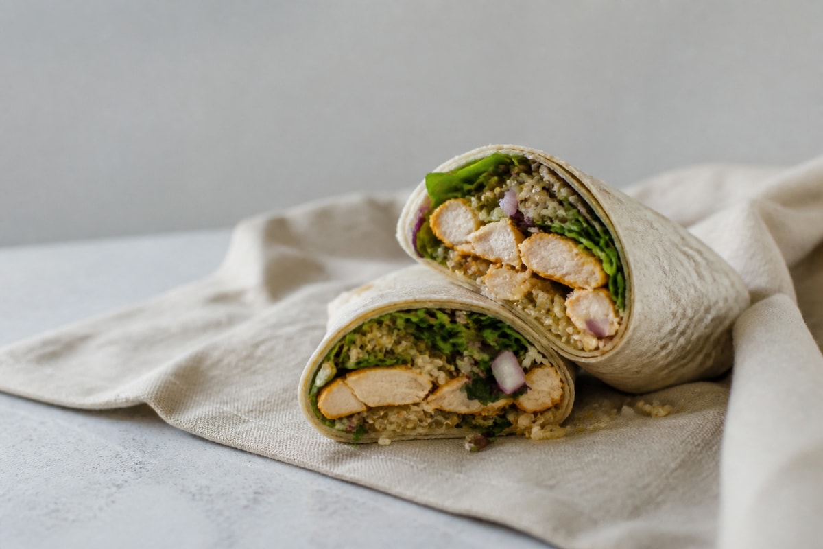 Chicken quinoa wrap cut in half on a board