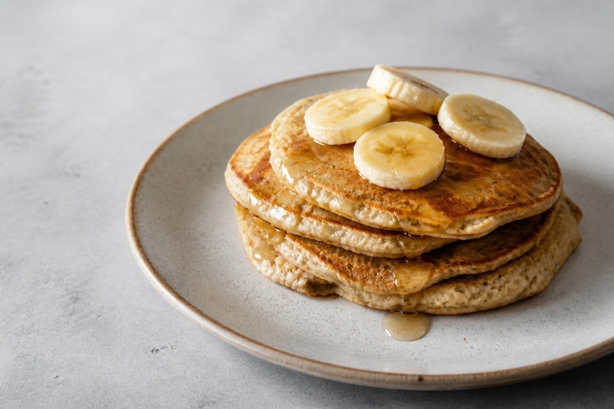 Stack of protein banana pancakes with yogurt and banana slices