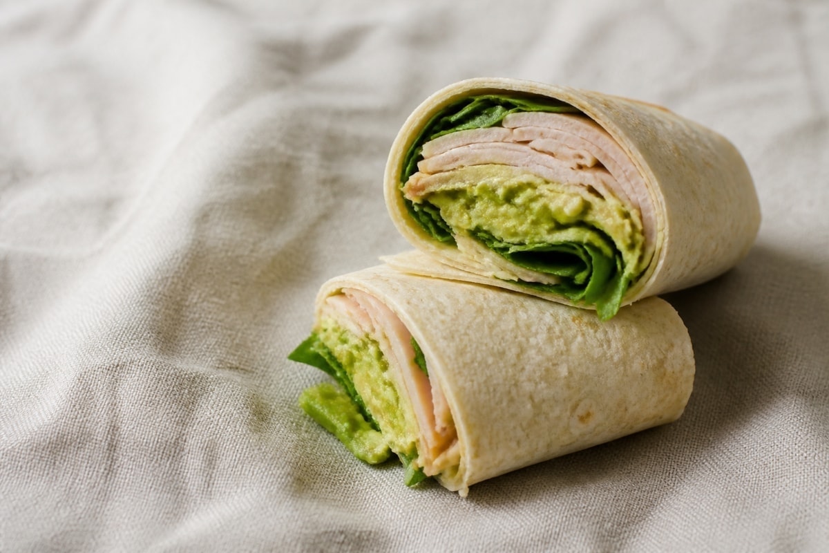 Turkey and avocado wrap cut in half with greens